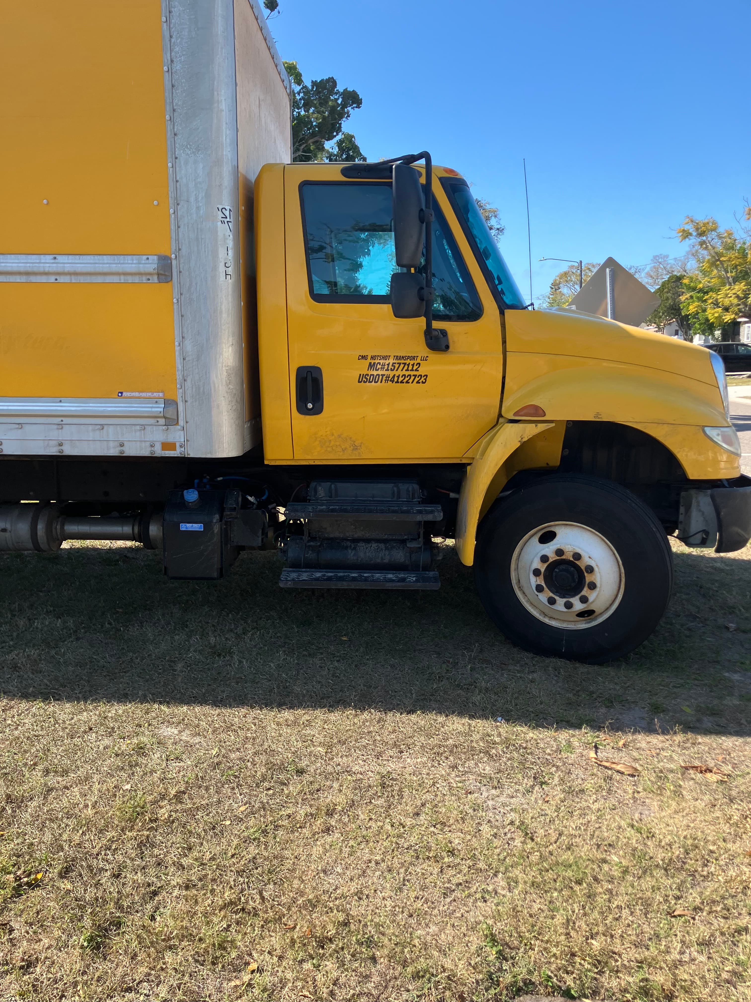 Yellow CMG 26ft box truck parked, dock-height with roll-up rear door