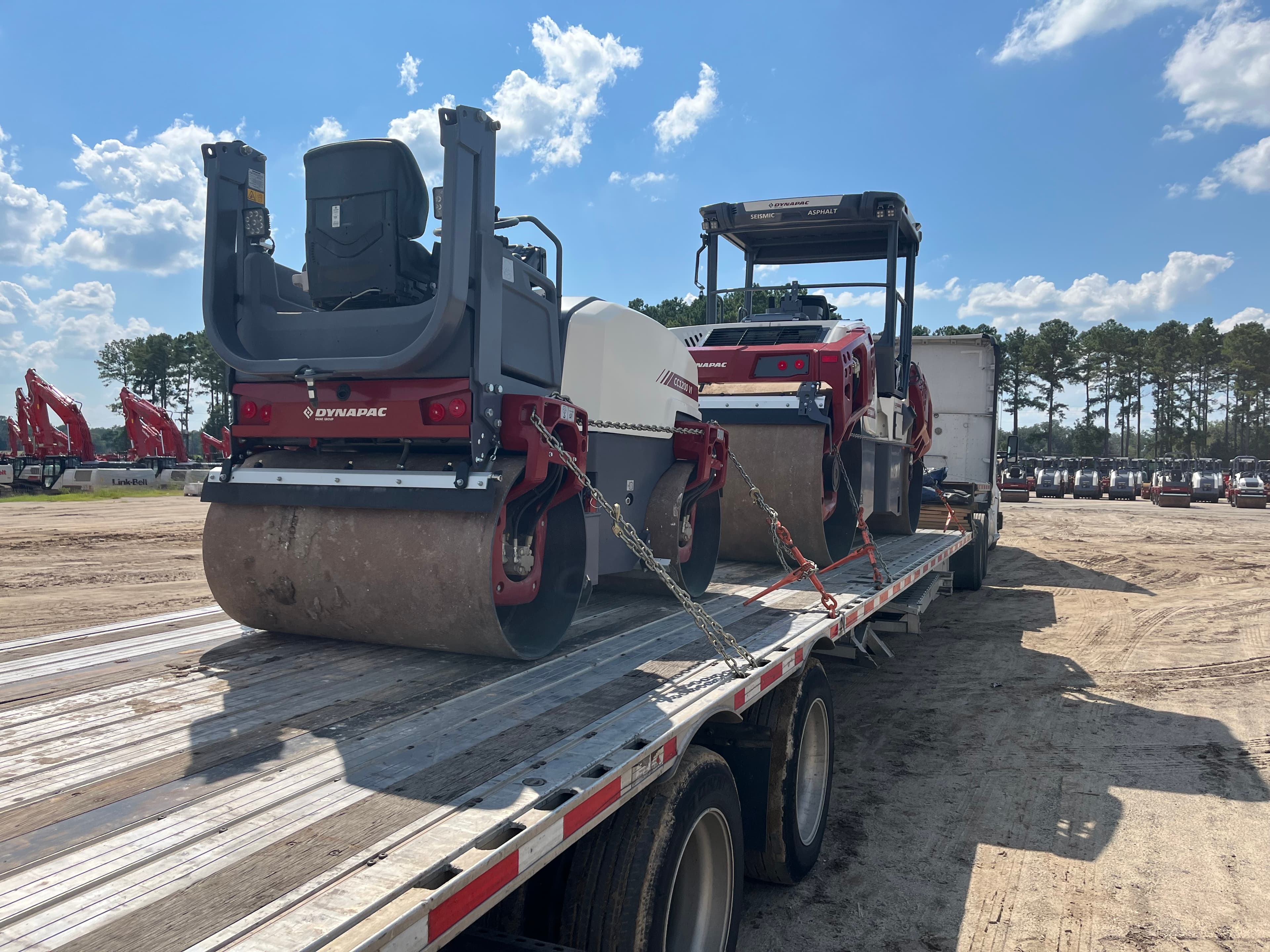 Heavy construction equipment loaded on a CMG flatbed for last-mile delivery
